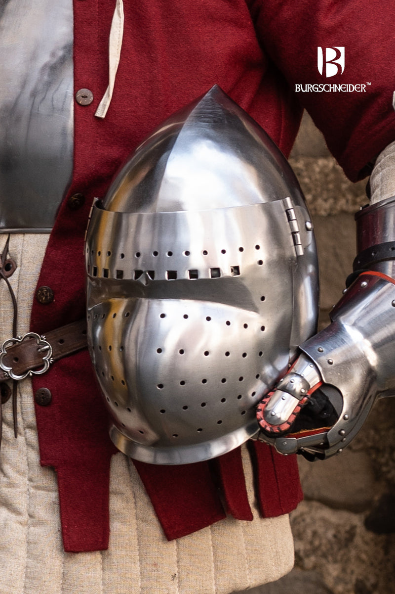 Close-up of a metallic medieval helmet with Burgschneider branding on a person wearing red armor.