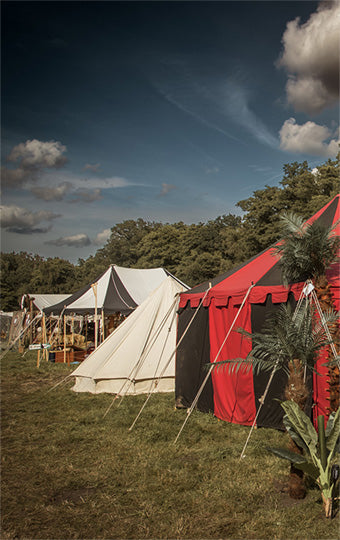 Tents set up in a grassy area with trees in the background