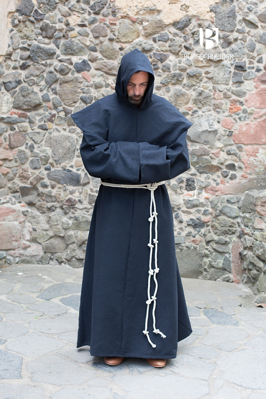 Person wearing a black hooded monk robe in front of a stone wall