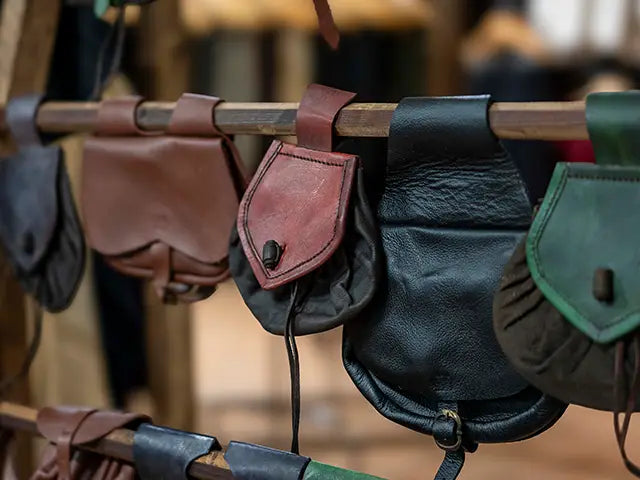 Collection of leather pouches hanging on a wooden rod with a blurred background