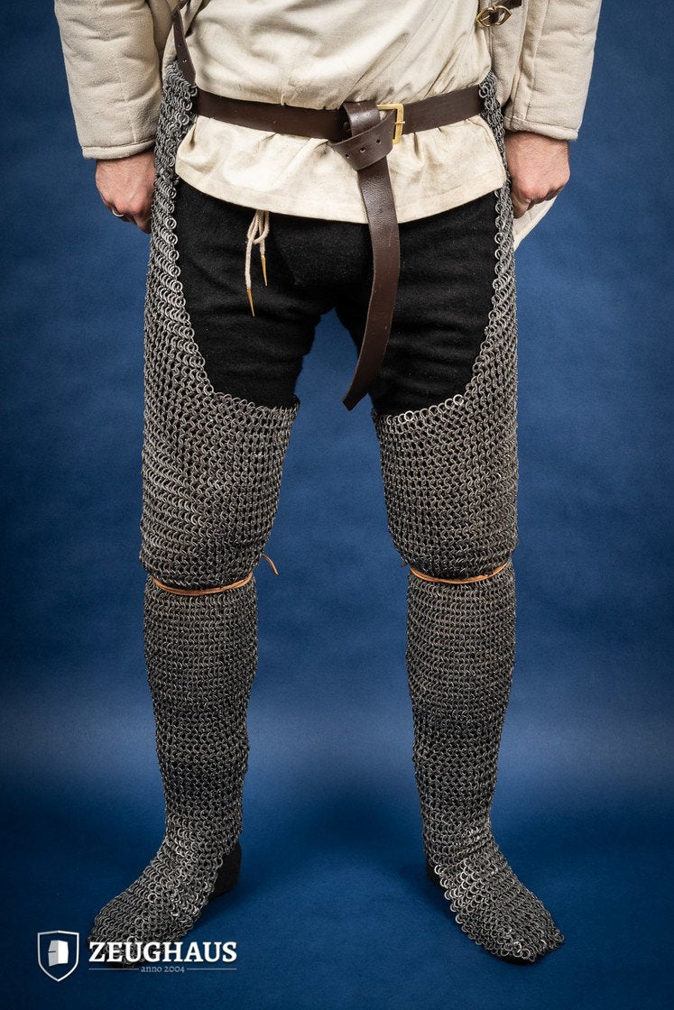 Person wearing chainmail leg armor on a blue background with 'Zeughaus' branding.