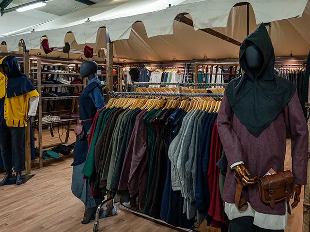 Clothing store with racks of clothes and mannequins wearing medieval clothing