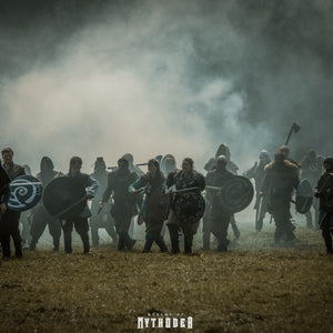Group of larp warriors in a foggy field with weapons and shields, featuring the logo 'Call of Mythber'.