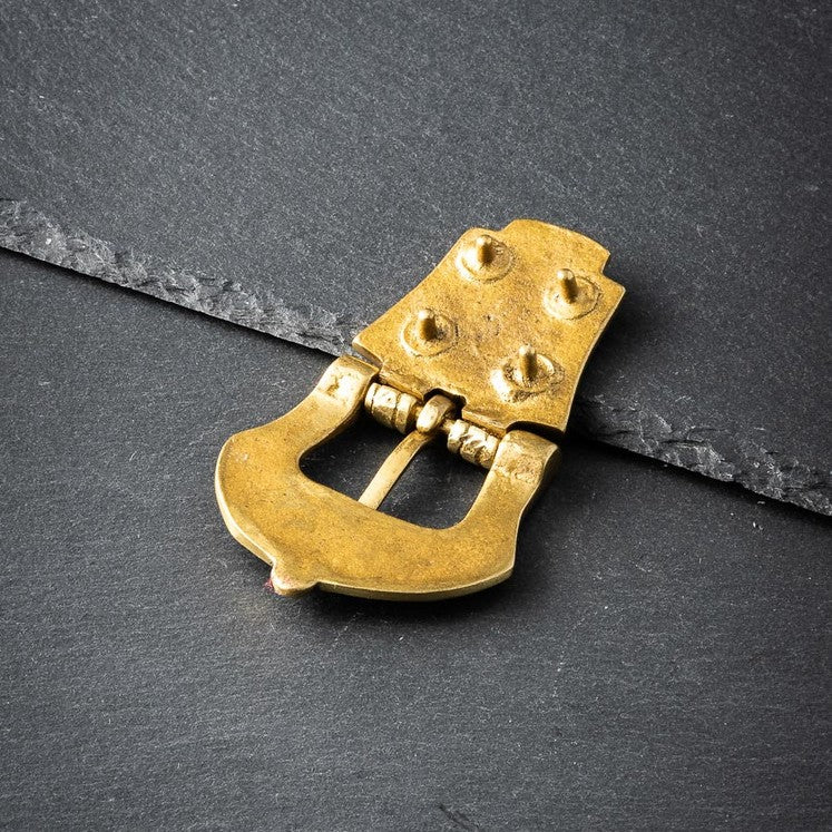 Gold metal belt buckle on a dark gray surface